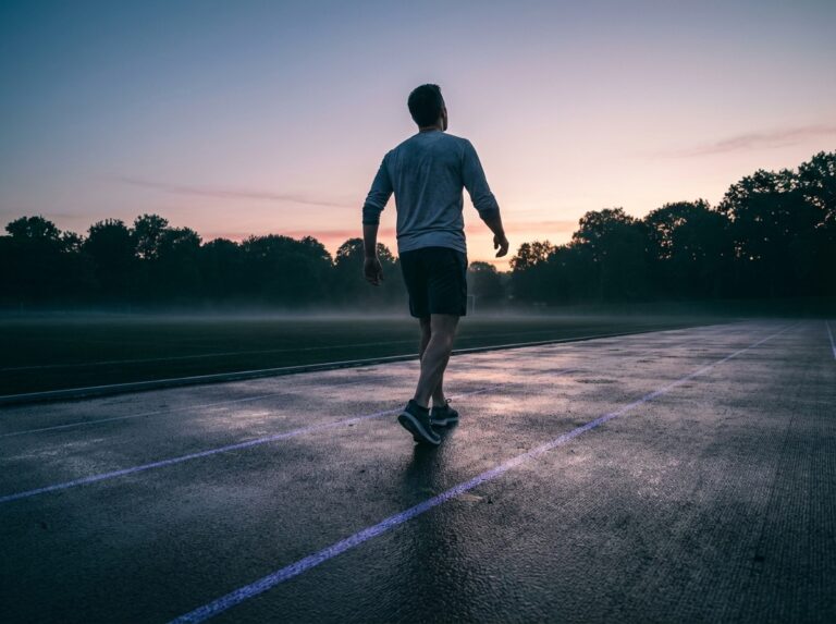 Man beginning a dawn warm-up jog on a damp outdoor track