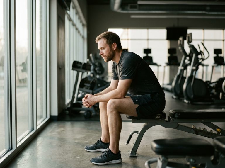 man contemplating recovery after workout in gym
